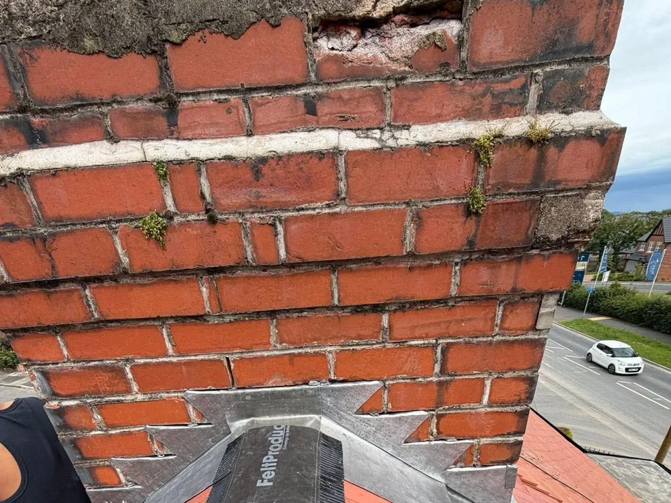 Red brick chimney with new lead flashing dressed into a grey ridge