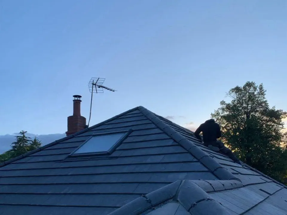 A finished dark hipped roof with a repointed chimney