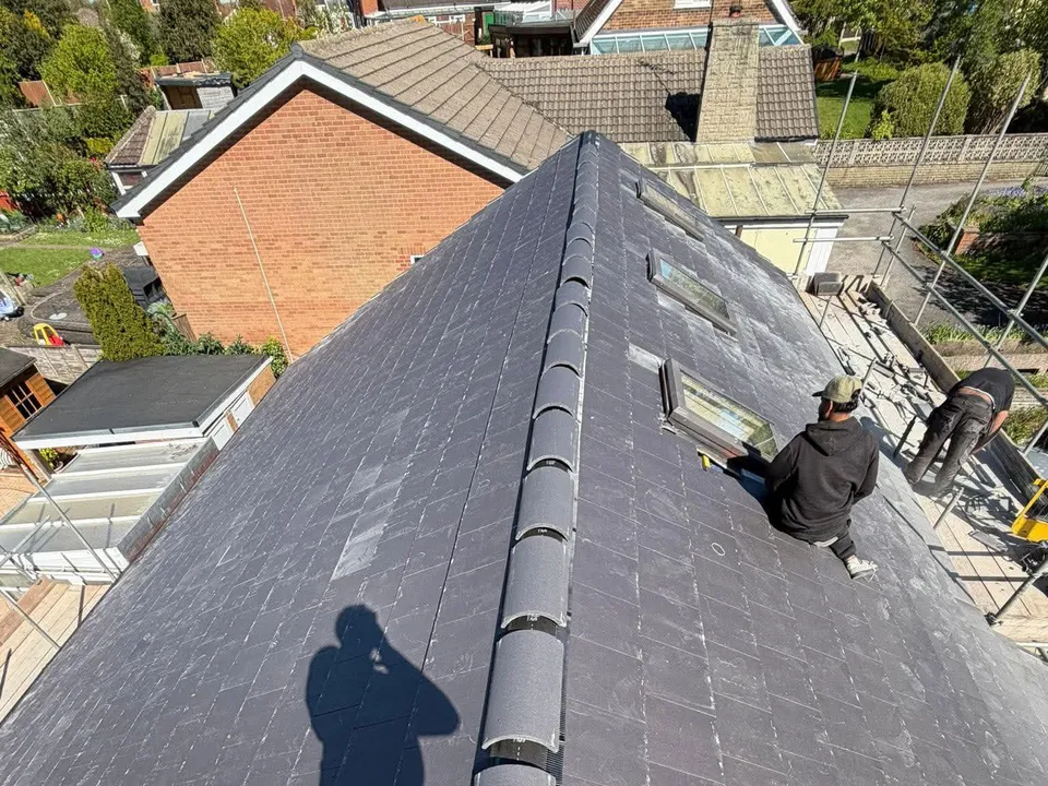 View along a new grey slate roof over houses