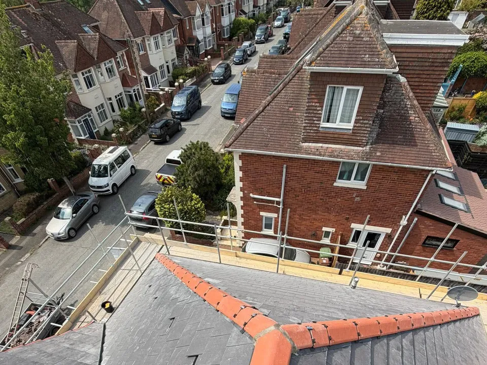 Orange ridge tiles meeting at a hip on a newly finished roof