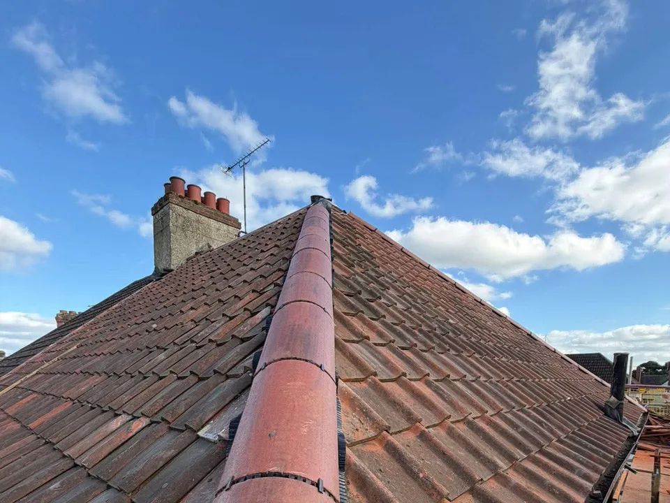 Red ridge tiles along a finished roof with a chimney