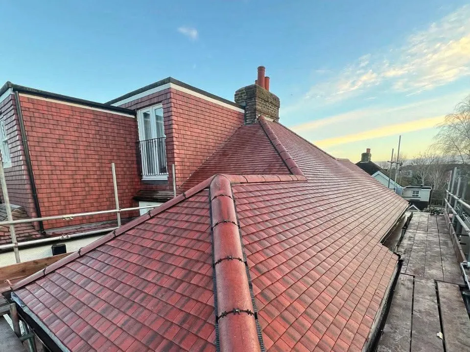 Newly finished red tiled roof and chimney under a golden evening sky